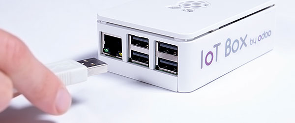 Một bàn tay đang kết nối USB với hộp IoT của Odoo